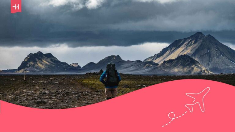 Un touriste vu de dos porta,nt un sac à dos marchant dans un paysage de geysers en Islande